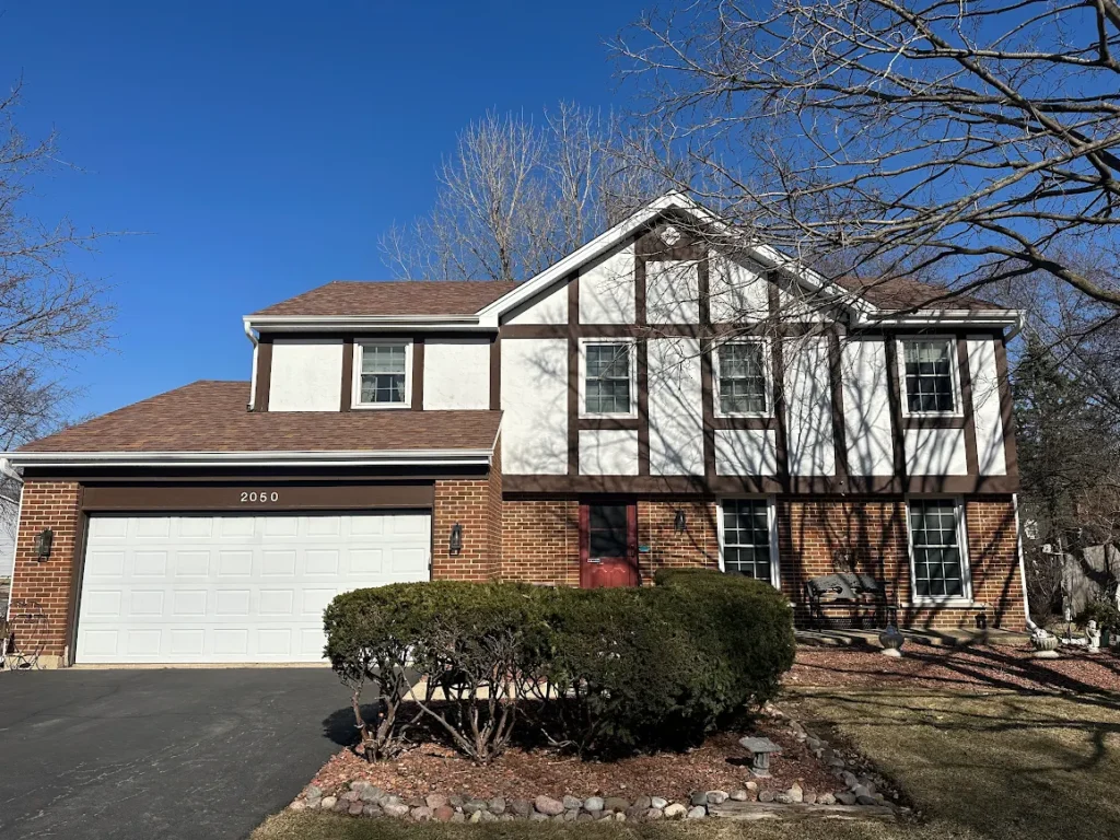 Two-story brick-and-white suburban house with a two-car garage and manicured front yard, address 2050.